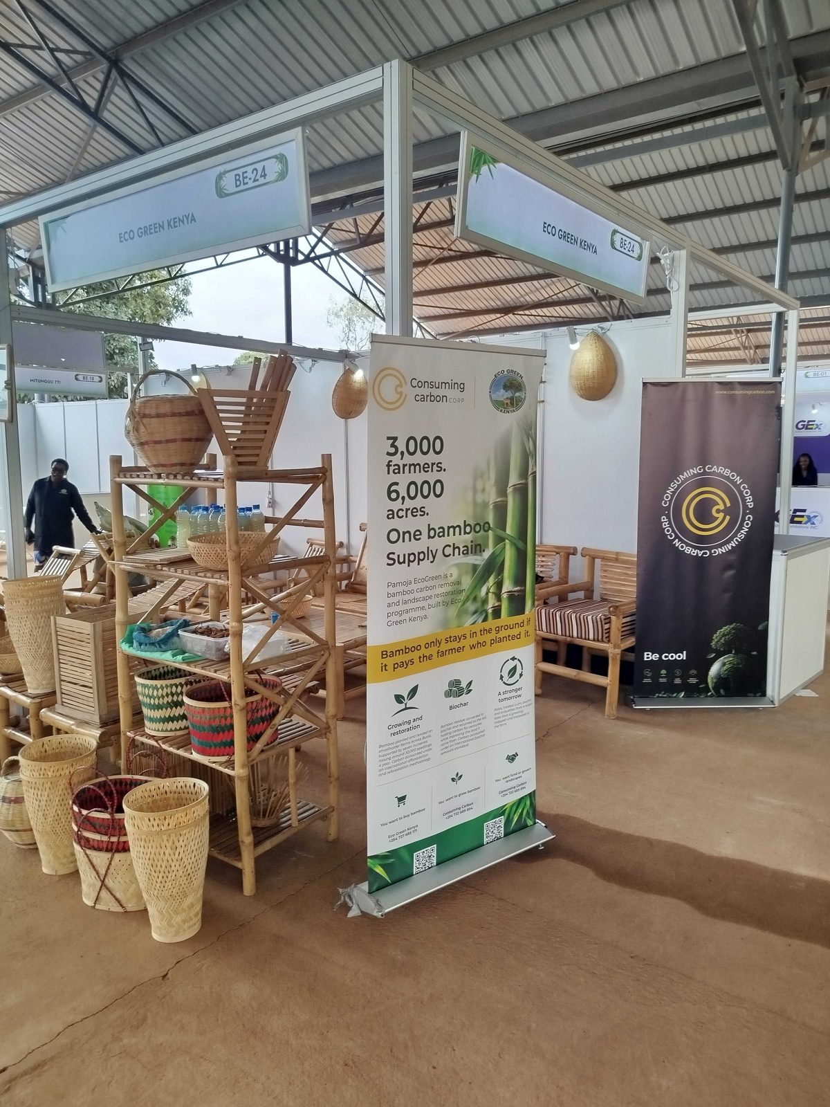 The shared Consuming Carbon and EcoGreen Kenya stand, with bamboo baskets, shelving and furniture, and a banner reading 'Bamboo only stays in the ground if it pays the farmer who planted it.'