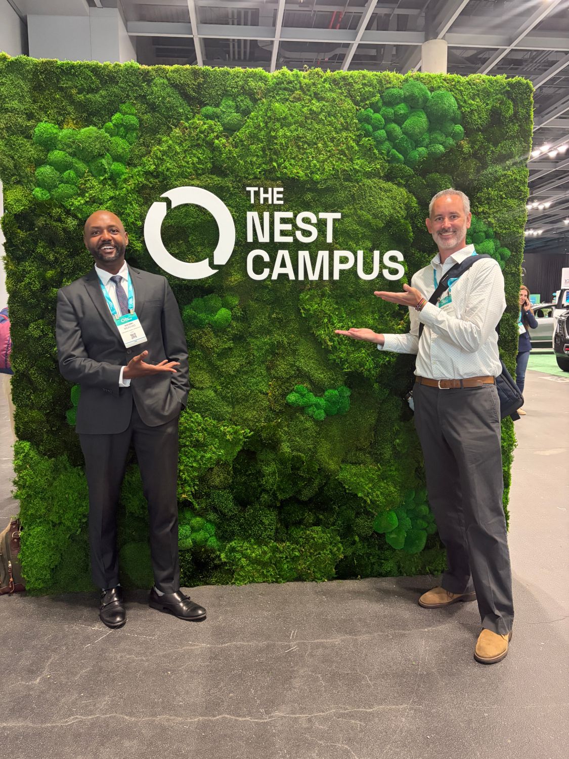 Zikki Munyao and Andrew McElfresh in front of a moss wall with The Nest Campus sign during Climate Week NYC.