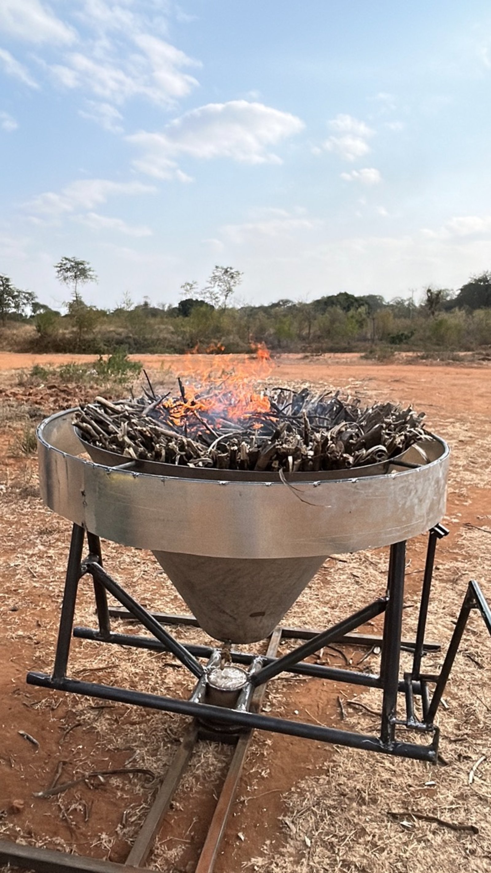 The Kontiki biochar kiln burning woody feedstock in Wamunyu, active flames visible at the kiln rim.